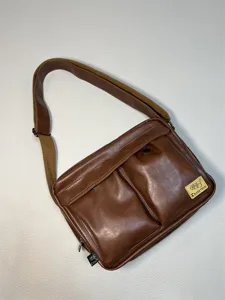 Detailed view of retro brown PU leather messenger bag with dual front pockets and strap.