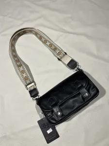 Detailed view of vintage black crossbody bag with wide ethnic strap and metal hardware details.