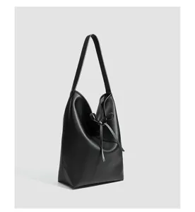 Detalle en primer plano del elegante bolso saco negro de cuero suave con lindo cordón.