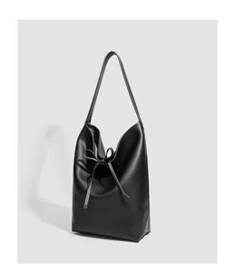 Primer plano detallado del bolso de hombro de cuero negro con su elegante cordón de lazo.