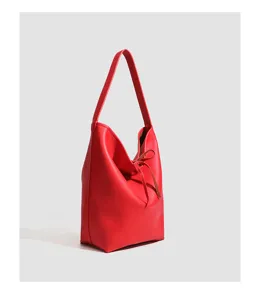 Primer plano detallado del bolso cubo de cuero rojo mostrando textura suave y correa.