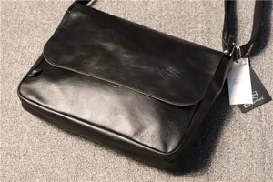 Close-up of the black leather messenger bag featuring front flap and brand logo detail.