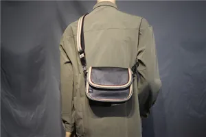 Detail view of casual mens crossbody bag featuring striped webbing strap and flap design.