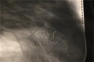 Close-up detail of men black leather messenger bag featuring debossed logo and texture.