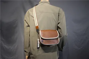 Men's casual brown leather crossbody bag with striped webbing strap and classic flap design.