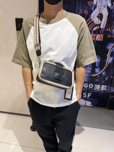 Details of the vintage men crossbody bag with striped strap and buckle closure on model.