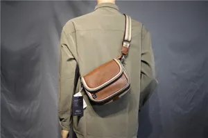 Casual brown leather crossbody bag with striped webbing strap and flap design for daily use.