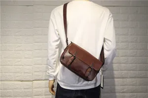 Detail view of mens vintage brown leather crossbody bag with double buckle flap design.