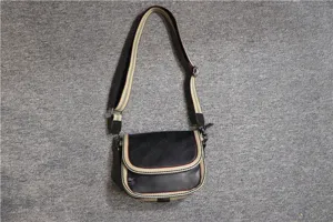 Close-up detail view of the casual black crossbody bag featuring stylish striped shoulder strap.