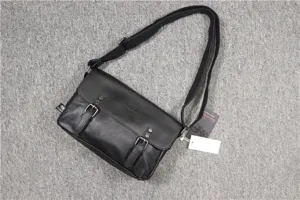 Black leather messenger bag detail showing retro buckle and adjustable strap features.
