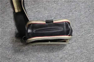 Men's fashion black leather crossbody bag with casual striped webbing shoulder strap detail.