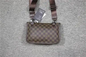 Vue detaillee du sacoche bandouliere a carreaux marron avec sangle et etiquette de marque.