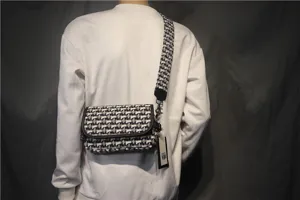 Gros plan détaillé du sac bandoulière élégant en toile noir et blanc avec large sangle.