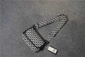 Vue détaillée d'un sac bandoulière en toile géométrique noire et blanche avec large sangle.