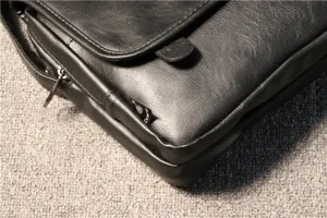 Détail en gros plan d'un sac messager en cuir noir avec étiquette latérale.