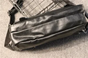 Sac messager en cuir noir pour homme détail gros plan texture, bandoulière style décontracté.