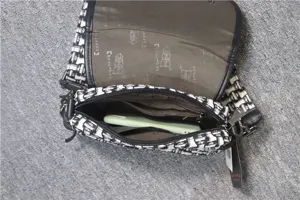 Vue détaillée de l'intérieur du sac messager tissé noir et blanc avec téléphone et poches.