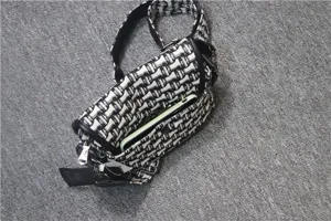 Vue détaillée du sac bandoulière en toile noir et blanc avec un motif classique et une poche.