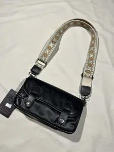 Detailed view of the black retro shoulder bag with ethnic wide strap and metal hardware.