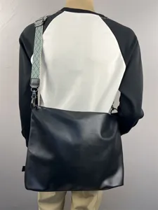 Detail view of men's large capacity black leather crossbody messenger bag with patterned strap.