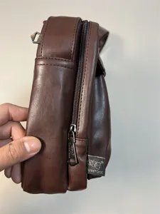 Detail view of men brown PU leather crossbody messenger bag with zipper and logo tag.