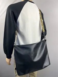 Detail view of men's black PU leather messenger bag with stylish patterned strap cross body.