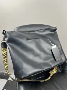 Black PU leather messenger bag detail showing wide geometric strap and metal hardware