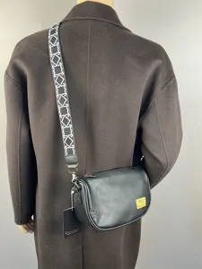 Black PU leather crossbody bag for men and women with patterned wide strap and front logo patch.