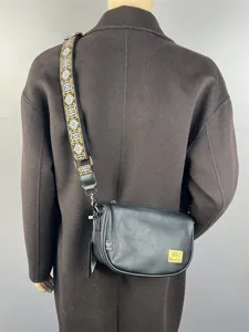 Stylish black leather cross-body bag for men and women, wide patterned strap and chic design.