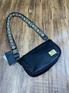 Detail view of the black leather crossbody bag featuring an embroidered wide strap and patch.