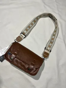 Three-box retro brown crossbody bag detailed view, featuring wide woven strap and leather flap.