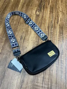 Detailed view of black PU leather crossbody bag with stylish patterned wide shoulder strap.