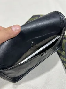 Black PU leather messenger bag detail showing interior pocket, magnetic snap closure and strap.