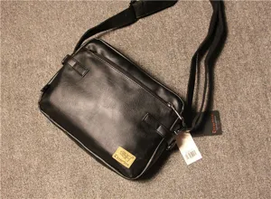 Detail view of black vintage men casual shoulder bag with adjustable strap and brand logo tag.