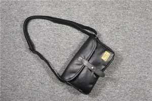 Close-up detail of the vintage black leather crossbody bag showing the flap and strap.