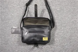 Detailed view of black PU leather crossbody bag zipper pocket and brand tag texture