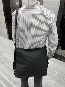 Vue arrière détaillée d'un sac cabas bandoulière souple noir en milieu intérieur.