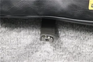 Detailed view of black vintage leather crossbody bag snap button hardware texture.