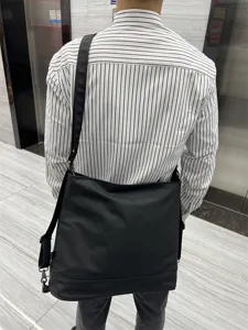 Grand sac cabas noir en cuir souple pour homme et femme, sac porte-epaule de travail elegant.