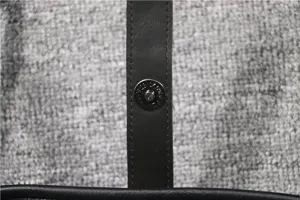 Detail view of the black leather crossbody bag strap featuring a durable metal magnetic snap button.