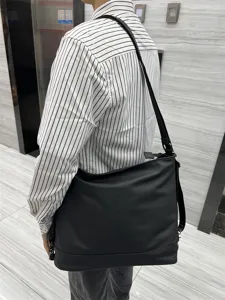 Vue detaillee du sac porte-epaule en cuir souple noir, montrant la sangle de transport pratique.