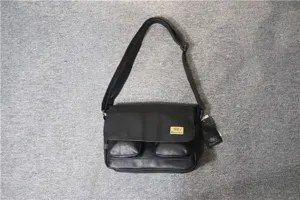 Detail view of black canvas messenger bag featuring dual front pockets and adjustable shoulder strap.