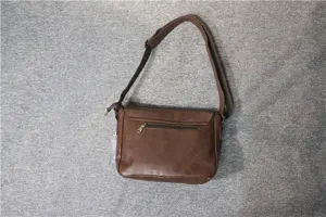 Detail view of brown leather messenger bag, adjustable crossbody strap and back zip pocket.