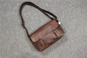 Detail view of vintage brown leather messenger bag with double buckles and strap.