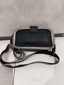 Black leather crossbody bag with vintage striped webbing trim and practical buckle closure for daily use.