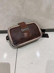 Retro brown PU leather crossbody bag detail featuring stylish striped trim and secure metal buckle.