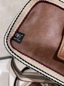 Close-up detail of retro striped crossbody bag showing leather texture and label.