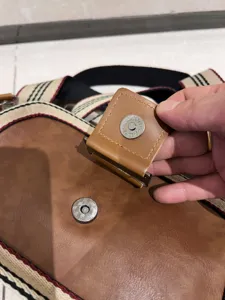 Detail view of men's retro striped crossbody bag magnetic buckle and quality strap design.
