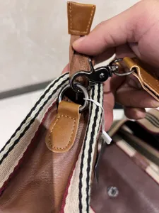 Detail view of vintage style messenger bag strap, featuring striped webbing and leather trim.