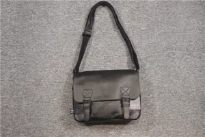 Close-up detail of the black leather messenger shoulder bag showing buckle and strap texture.